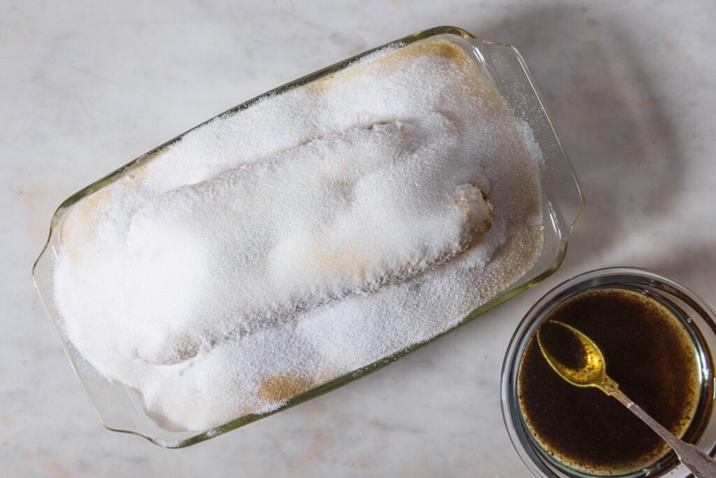 Carrots coated in salt in an oven dish. The salt is slightly brown from baking.