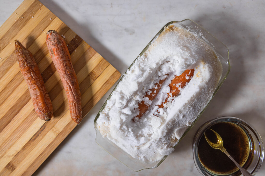 Carrots being peeled out of their salt crust, where they were baked in.