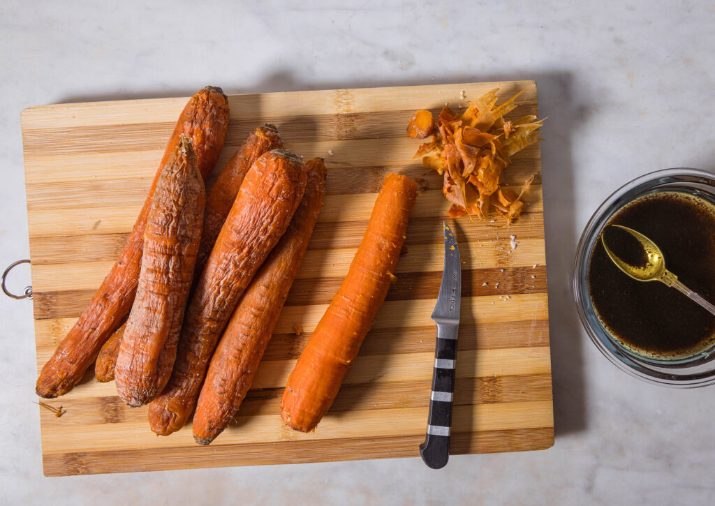 Baked carrots being peeled.