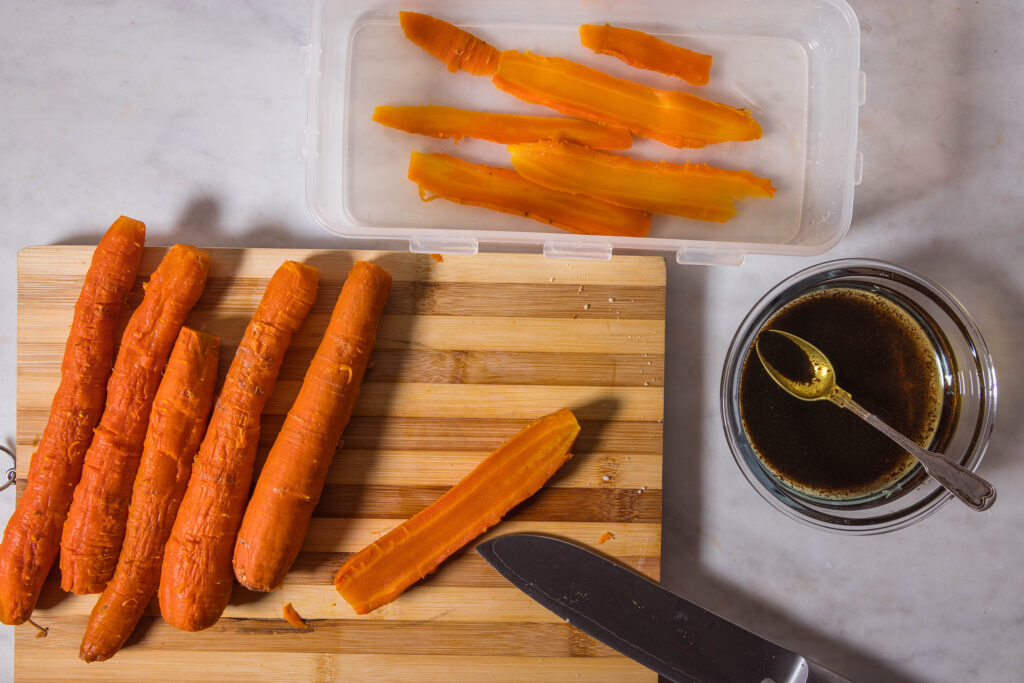 Baked carrots are being cut into very thin slices